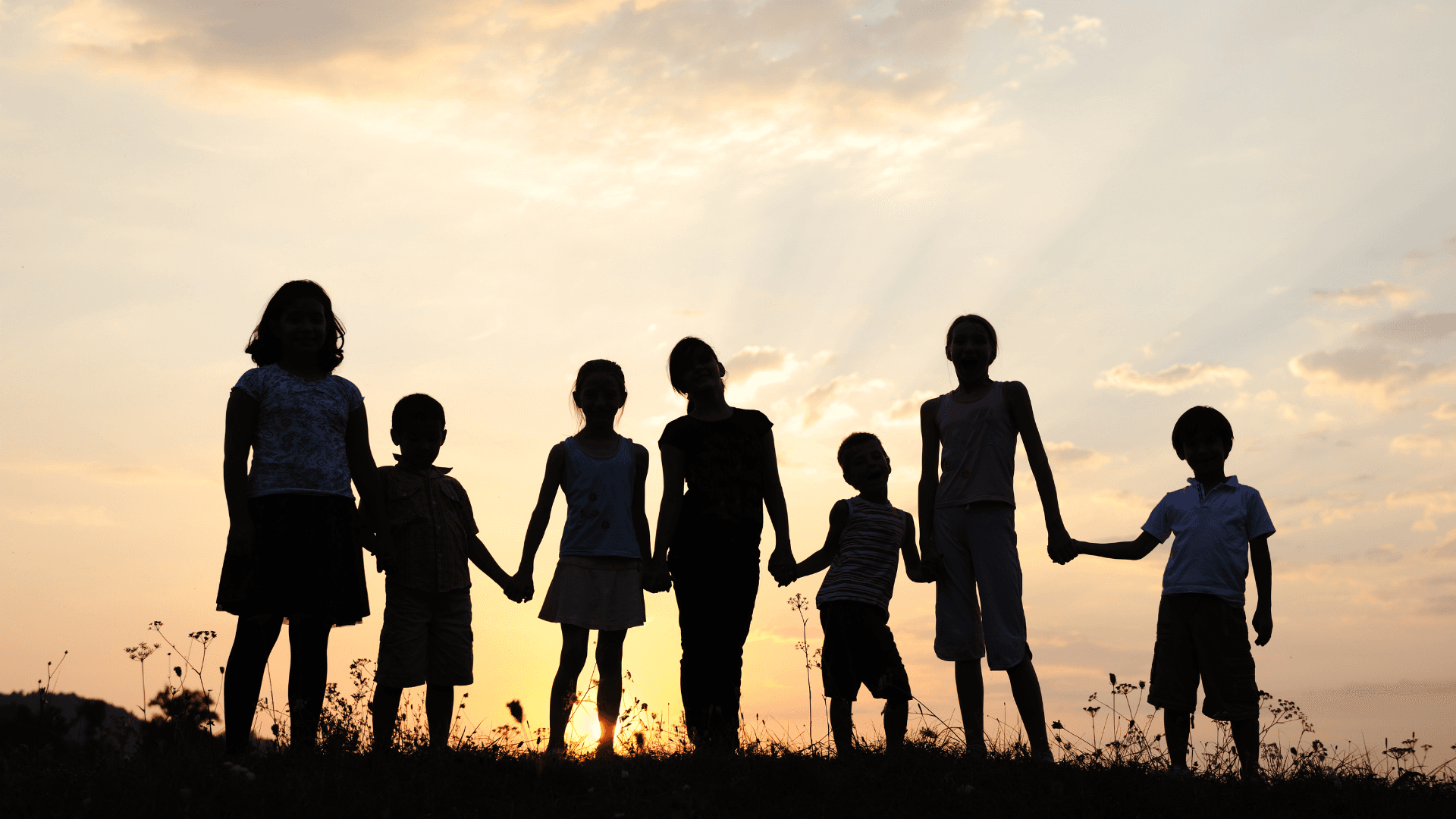Children holding hands at sunset